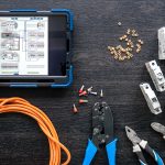 Flat lay composition with electrical tools and digital tablet on wooden background.