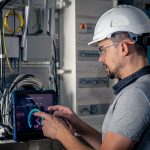 Man, an electrical technician working in a switchboard with fuses. Installation and connection of electrical equipment.